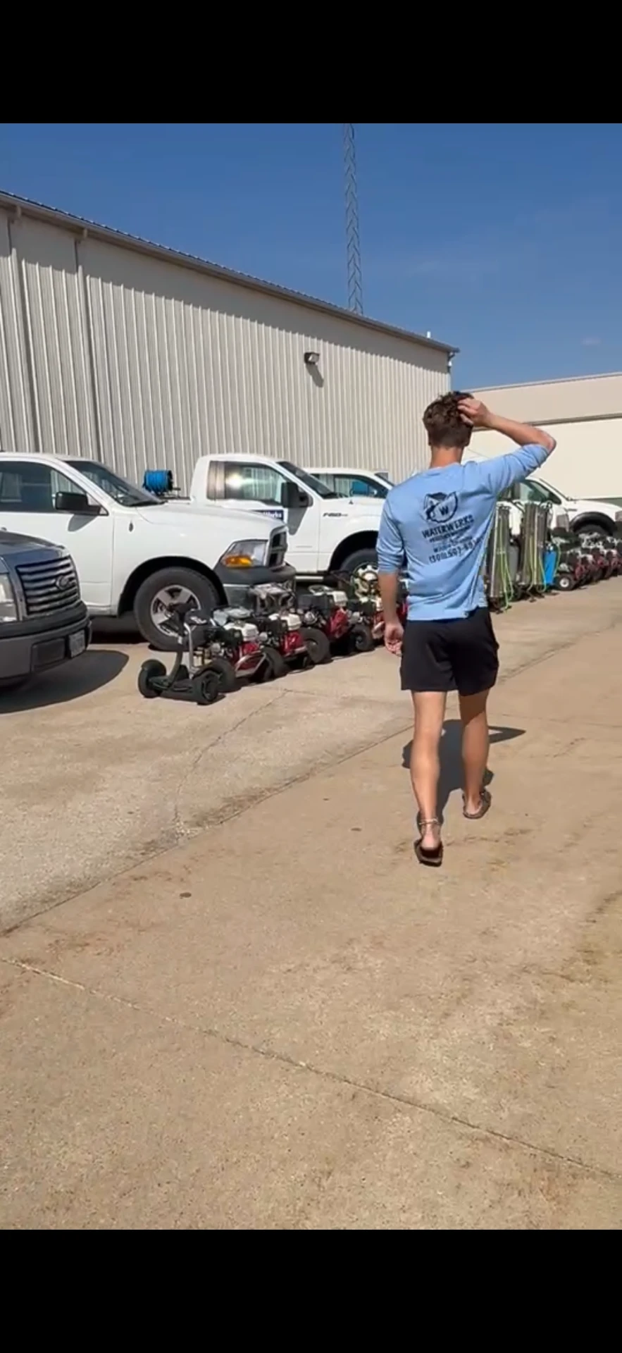 Alex Snyder walking through the shop floor with window cleaning trucks and equipment